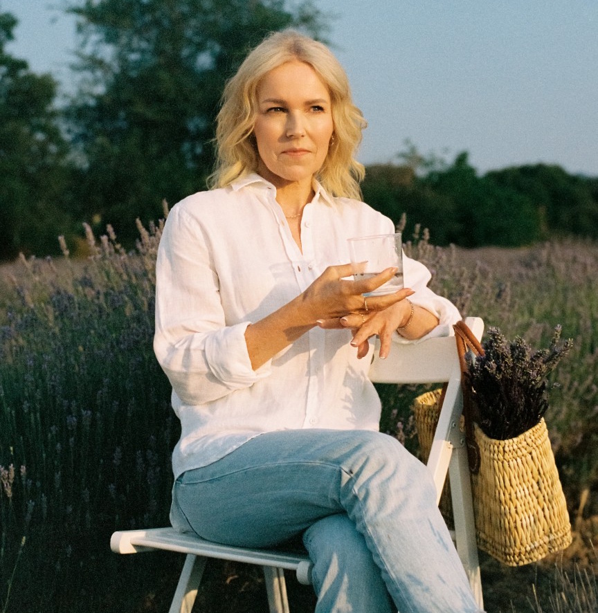 Dr Berit Nordstrand sitting in a lavender field, holding a glass of water